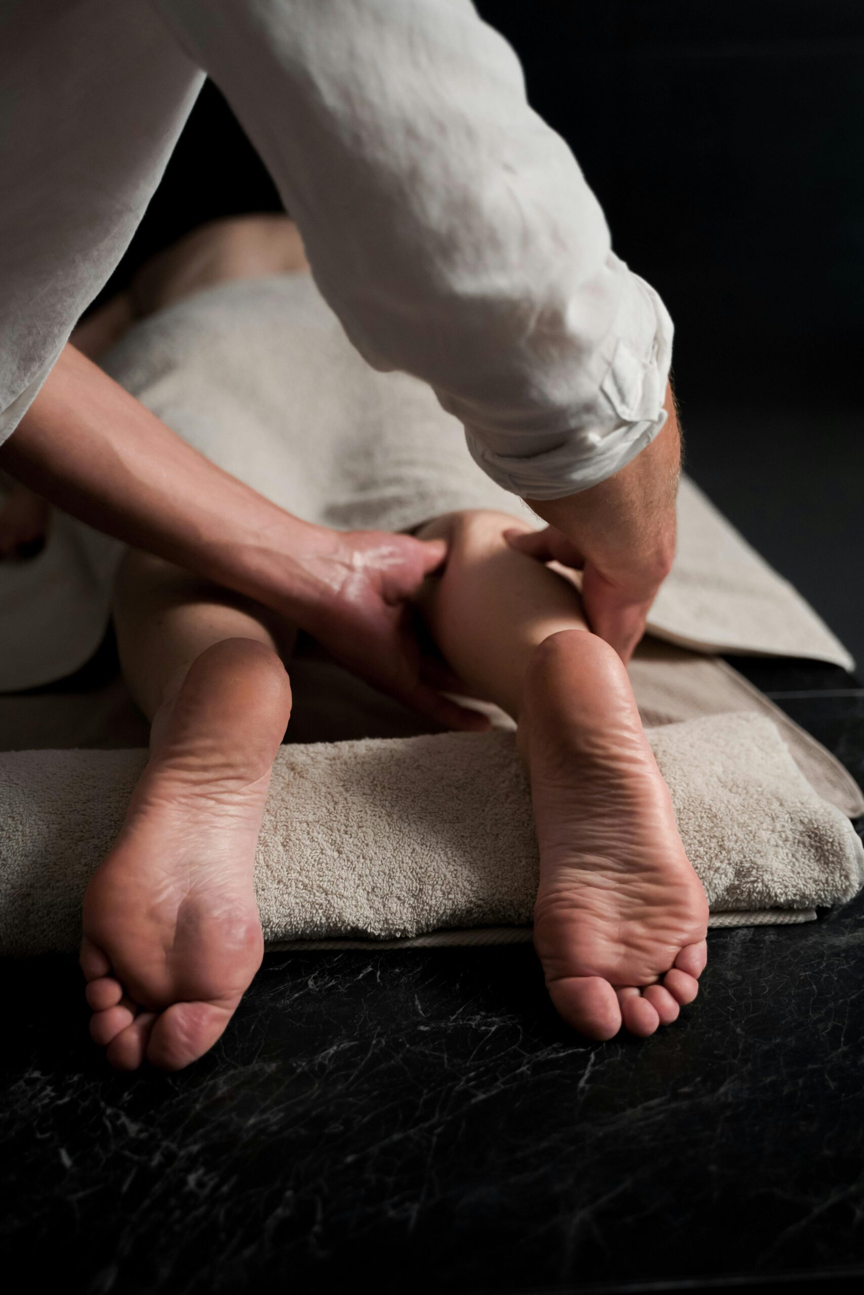 Mãos de um terapeuta aplicando massagem relaxante nos pés de uma pessoa idosa para alívio de dores e melhora da circulação.